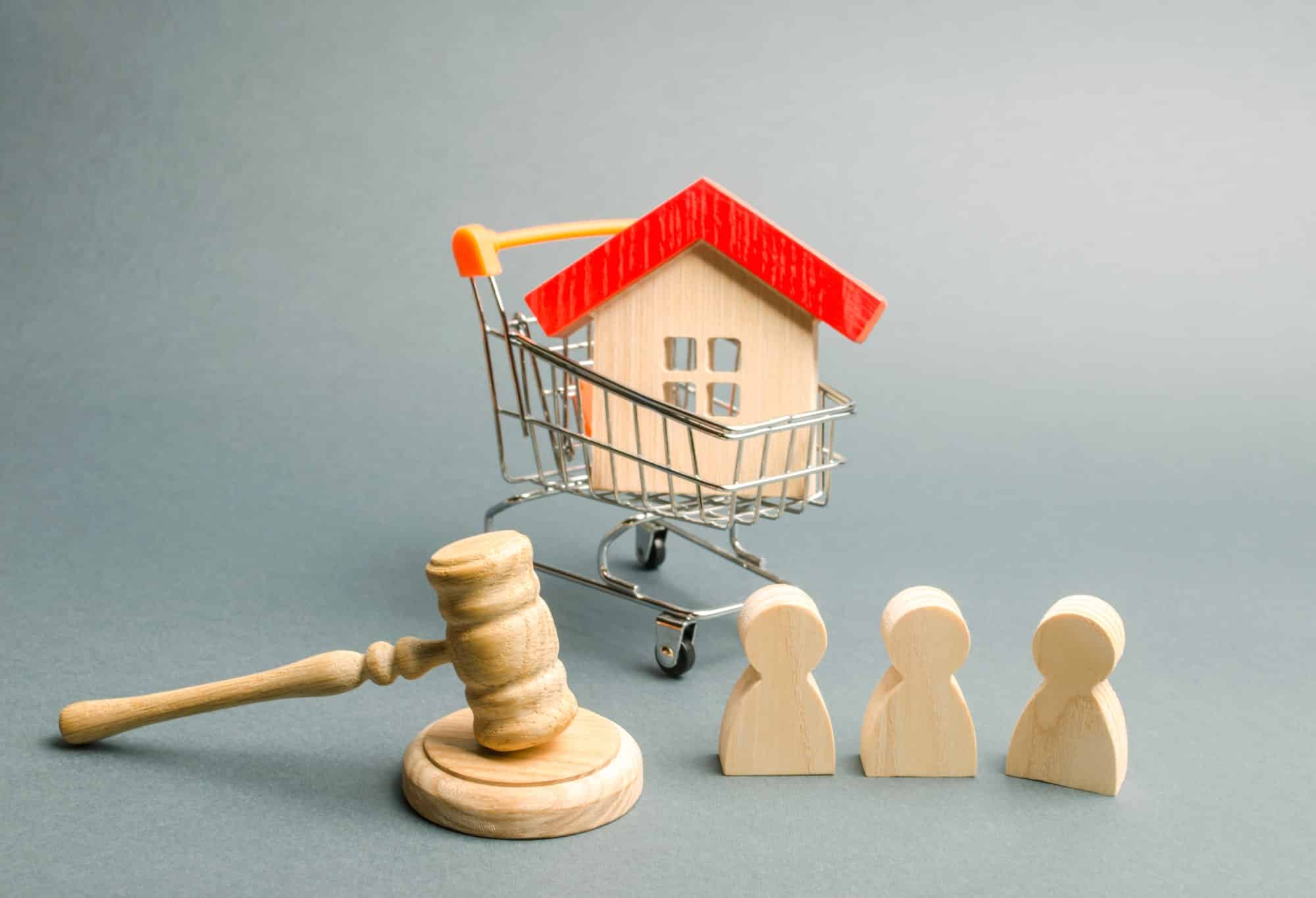 Wooden figures of people, a house in a supermarket trolley and a judge